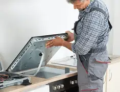 Appliance repair technician installing a built-in cooktop in Grand Rapids, MI