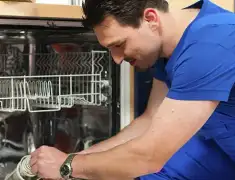 Dishwasher repair technician inspecting and servicing an open dishwasher in Grand Rapids, MI