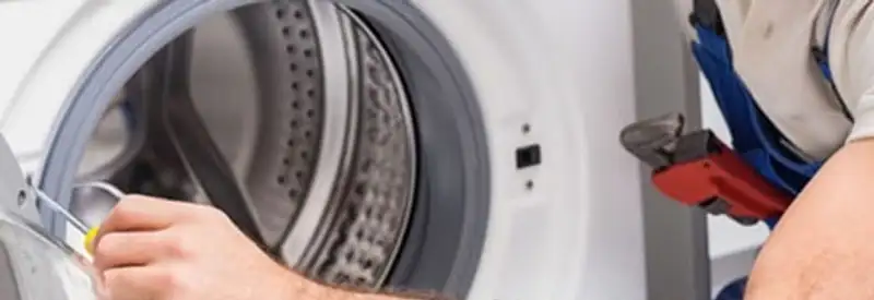 Appliance technician repairing a clothes dryer drum and internal parts in Grand Rapids, MI