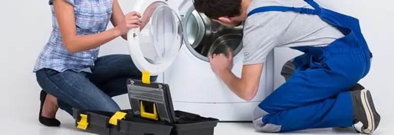 Washer repair technician inspecting a front-load washing machine with tools in Grand Rapids, MI