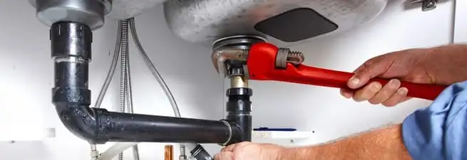 Garbage disposal repair technician tightening the sink drain and disposal connection in Grand Rapids, MI