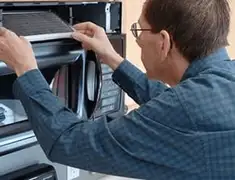 Appliance repair technician replacing a microwave vent filter in Grand Rapids, MI