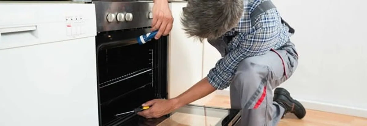 Oven repair technician inspecting and servicing an electric oven in Grand Rapids, MI
