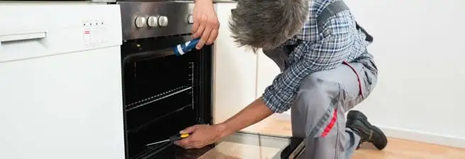 Oven repair technician inspecting and servicing an electric oven in Grand Rapids, MI