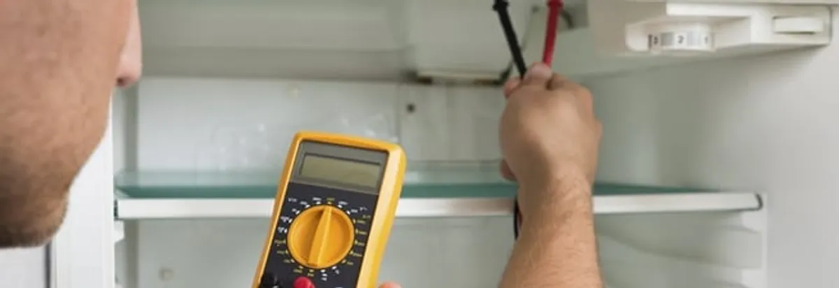 Refrigerator repair technician testing electrical components with a multimeter in Grand Rapids, MI