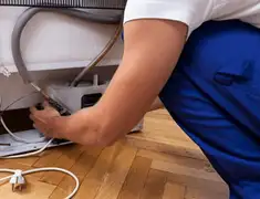 Appliance repair technician fixing refrigerator water line and connections in Grand Rapids, MI