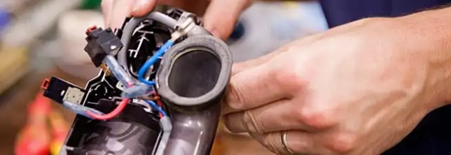 Vacuum repair technician reconnecting wiring and components in Grand Rapids, MI