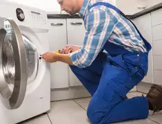 Washing machine repair technician servicing a front-load washer in Grand Rapids, MI
