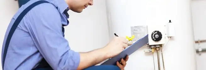 Water heater repair technician inspecting the unit and recording service notes in Grand Rapids, MI