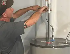 Water heater repair technician tightening supply line connections in Grand Rapids, MI