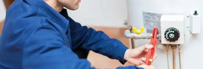 Water heater repair technician adjusting the temperature control and gas valve in Grand Rapids, MI